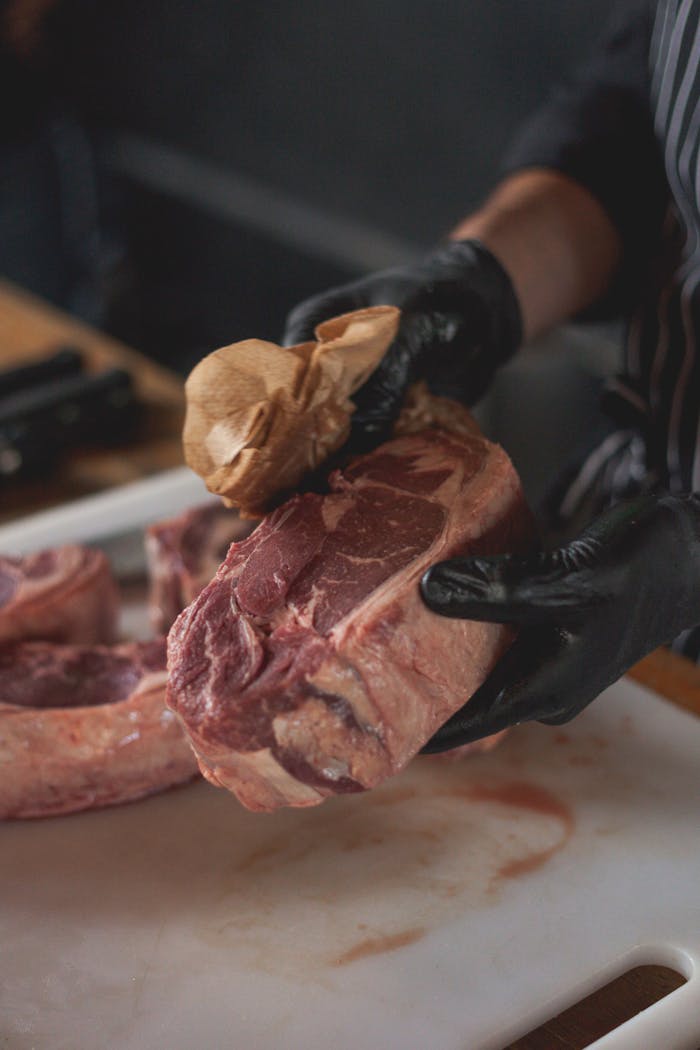 The Art of Drawing Readers In: Your attractive post title goes here Close-up of a chef wiping fresh raw beef steak with paper towel on a chopping board.